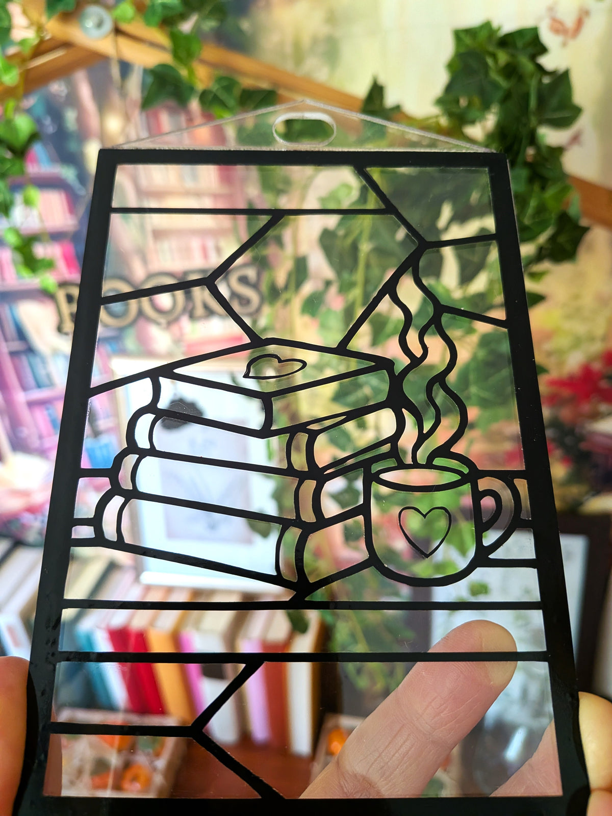 Nahaufnahme des noch nicht ausgemalten DIY-Sonnenfängers „Booklove“ mit drei Büchern und einer dampfenden Tasse mit Herzmotiv