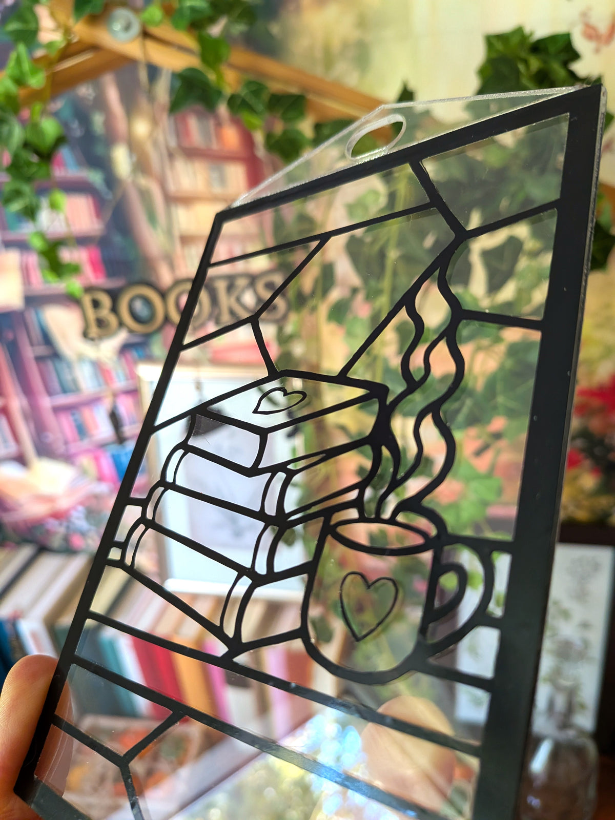 Seitlich fotografierter DIY-Sonnenfänger „Booklove“ mit Buchstapel, dampfender Tasse und sichtbarer Aufhängung