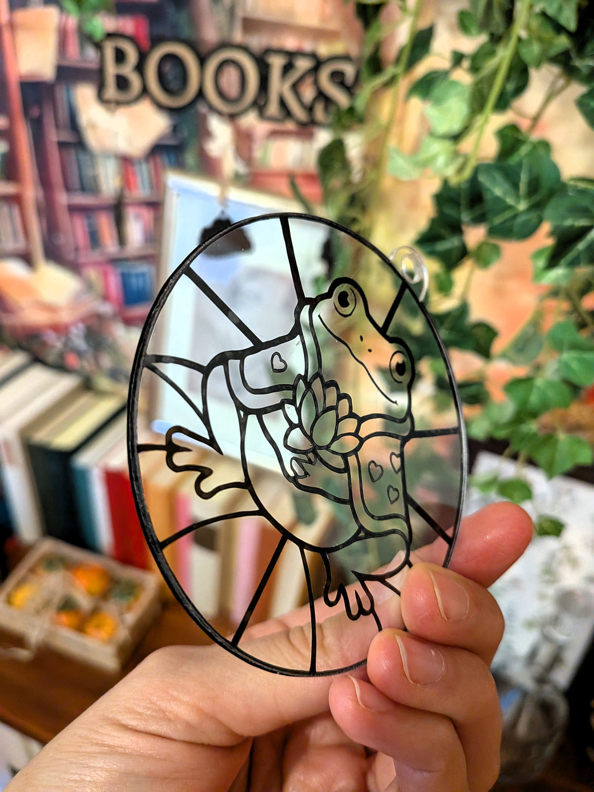 Unbemalter DIY-Sonnenfänger mit Frosch Valentin und Seerosenblüte, schräg in der Hand gehalten.