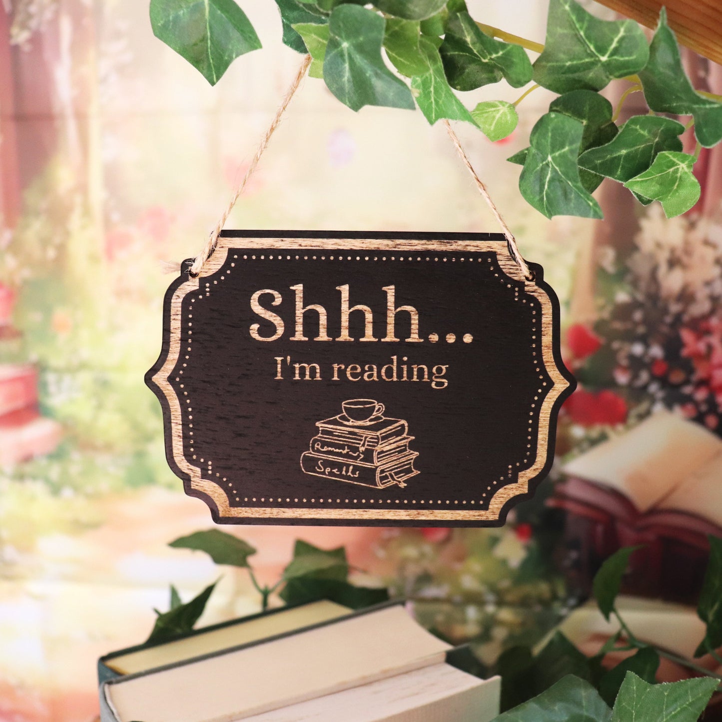 Holzschild mit Jutekordel und Gravur vor Bücherregal im Hintergrund gemütlich, warme Farben